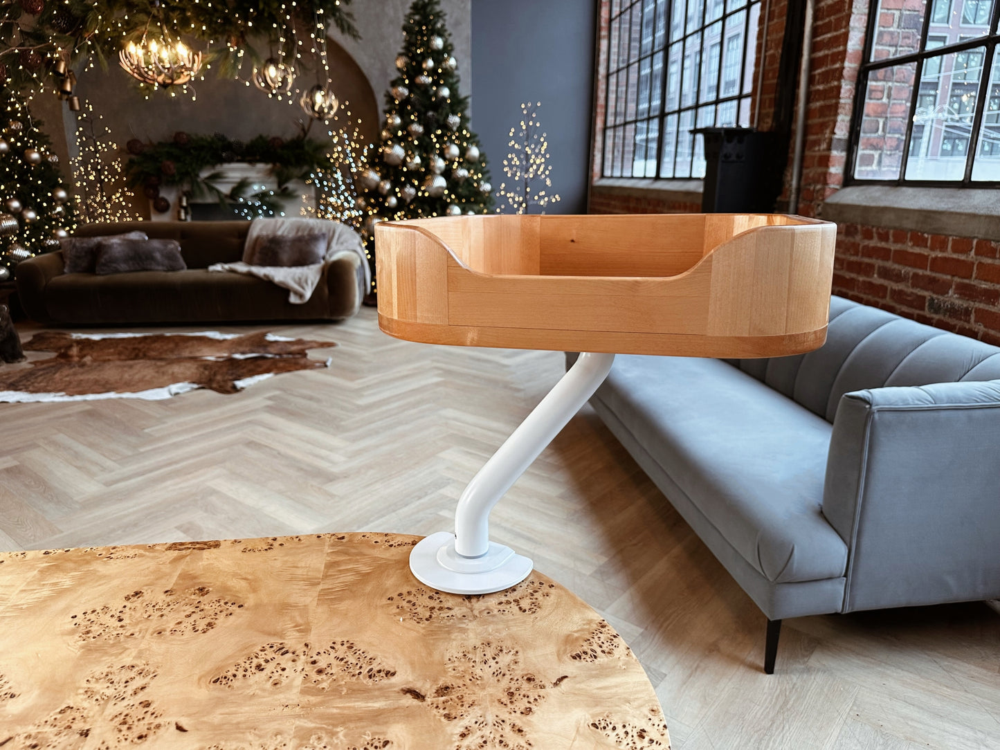 Empty wooden ERGO PURRCH™ desk-mounted cat bed with a white arm, showcased in a modern loft with festive holiday decor, Christmas tree, and warm lighting.